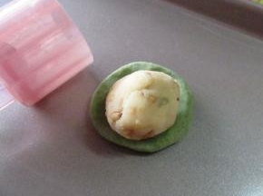 然后用绿色皮包裹馅料包严实放入模具中