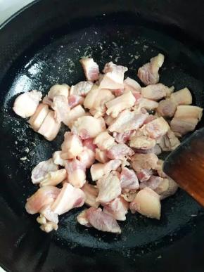 锅中加油烧热后倒入五花肉煸炒至析出油分，表面金黄