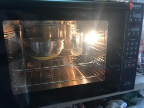 现在天气比较热，不需要开烤箱温度辅助发酵，直接把面盆包保鲜膜，烤箱中放一杯热水进行发酵