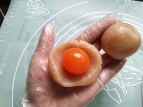 莲蓉馅窝成圆形，放入一个蛋黄，包圆