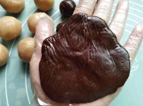 取一个饼皮，在手心里按扁，一定要带手套操作哦