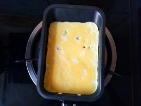 倒入一半的蛋液，晃动小锅，使蛋液铺满锅底。开小火。