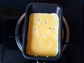 倒入一半的蛋液，晃动小锅，使蛋液铺满锅底。开小火。