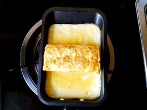 小锅中倒入剩余的一半蛋液，小火煎，在将要凝固的时候把刚刚煎好的蛋卷放在中间部位