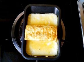 小锅中倒入剩余的一半蛋液，小火煎，在将要凝固的时候把刚刚煎好的蛋卷放在中间部位