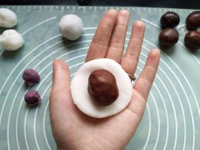 取一个白色面团，按扁包入豆沙馅