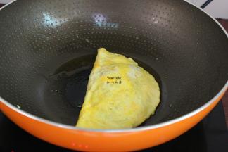 把鸡蛋另外一边翻转包裹米饭，用锅铲压边缘，黏住；