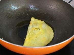把鸡蛋另外一边翻转包裹米饭，用锅铲压边缘，黏住；