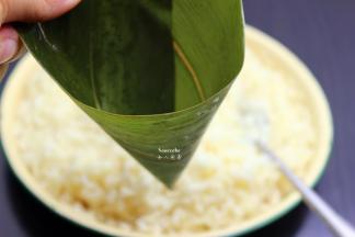 洗净干净的粽叶折叠成漏斗形状，但不能漏；