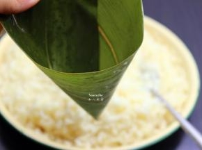 洗净干净的粽叶折叠成漏斗形状，但不能漏；