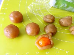 莲蓉馅用手掌压扁，包裹上蛋黄，用虎口一点点收好收口