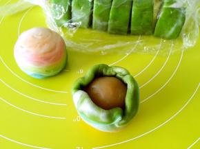 包裹上莲蓉蛋黄馅，一点点推面收好收口，收口朝下放，之后整理下蛋黄酥，将螺旋的中心放在最顶端