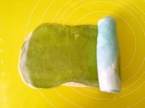 将擀好的面团由浅色向深色卷起来