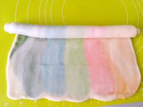 将擀好的面团卷起来，如图将5条颜色顺着卷起来，之后盖保鲜膜松弛15分钟