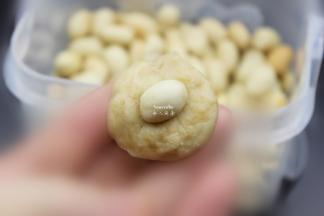 取一粒花生米，放入包裹，揉成光滑小圆；