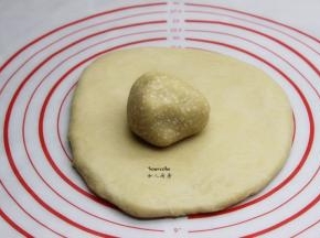 油酥面团放在擀开的油皮面团上，压扁，用擀面杖压一压，均匀的铺在油皮上；