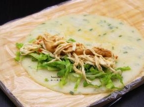 煎好的鸡蛋香葱饼，放入鸡丝肉、生菜、香葱、花生酱，卷起了，中间切段；