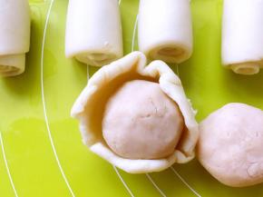 包裹上红豆沙，收好收口，之后用擀面杖轻轻擀成圆饼，再用刀划两刀