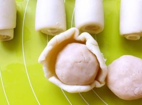 包裹上红豆沙，收好收口，之后用擀面杖轻轻擀成圆饼，再用刀划两刀