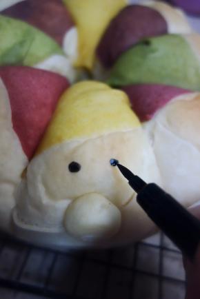 面包烤熟后放在烤架上晾凉脱模，用巧克力笔或者色素笔画出眼睛，房子的窗户等等