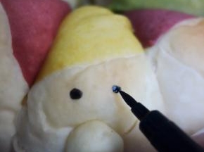 面包烤熟后放在烤架上晾凉脱模，用巧克力笔或者色素笔画出眼睛，房子的窗户等等
