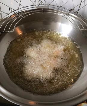 手上蘸淀粉水，取适量饭团搓成圆形放入烧热的油锅中炸