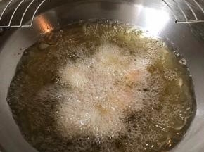 手上蘸淀粉水，取适量饭团搓成圆形放入烧热的油锅中炸