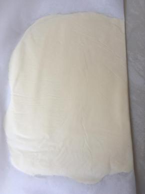 将裹酥皮用的黄油切小块铺在油纸上，盖上油纸，擀面杖擀成薄片，一起送冰箱冷冻