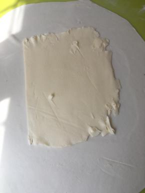 冰箱取出黄油片，将包裹的油纸去掉，放擀好的面片中间