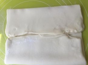 四个角向中间折，把黄油全部包裹在面团里，擀成长方形，之后两边向中间在对折