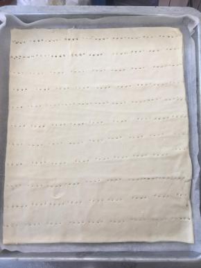 裁掉不规则的边角，盖保鲜膜松弛半个小时，烤箱预热180度，将松弛好的面团连底下的油纸一起放入烤盘，烤半个小时，表面焦黄，出炉凉透备用