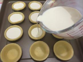 9. 把蛋挞液倒进挞皮中，倒至7—8分满，用量杯就是方便（我用的是法焙客的玻璃量杯）