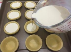 9. 把蛋挞液倒进挞皮中，倒至7—8分满，用量杯就是方便（我用的是法焙客的玻璃量杯）