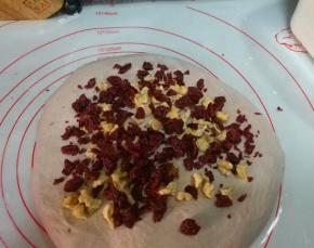 取出面团，按扁，撒上一半的核桃碎和蔓越蔓碎；