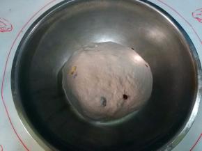 然后面团对折，揉圆成团，尽量把果仁碎包在面团里。将面团放容器中，盖上保鲜膜进行发酵；