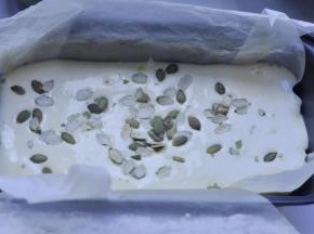 10、将完全混合均匀的蛋糕糊，从20CM高度倒入垫有油纸的模具，在蛋糕糊面上撒上南瓜子。