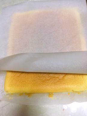 再取一张油纸，盖在常温的蛋糕上，连油纸一起反转过来，一点点揭开之前底层的油纸，揭出毛巾面