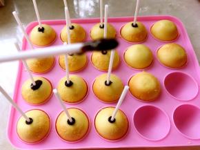 棒棒糖纸棒沾少许巧克力，插在蛋糕上，之后放在模具上等20分钟左右，让巧克力凝固，我是放冰箱冷藏了一会，很快就凝固啦