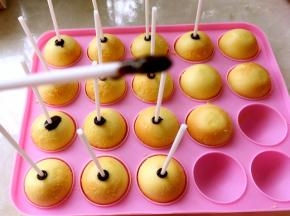 棒棒糖纸棒沾少许巧克力，插在蛋糕上，之后放在模具上等20分钟左右，让巧克力凝固，我是放冰箱冷藏了一会，很快就凝固啦