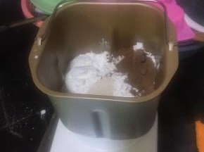 将准备的材料除黄油外，按鸡蛋，牛奶，盐，糖，中筋粉，干酵母，可可粉的顺序放入面包机桶
