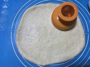 松弛好的面团檊成1CM厚的面片，用甜甜圈模具压出形状，如果面团不好擀说明松弛不到位，边角面片可重新整理擀开后用模具按压。