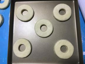 将已经成形的甜甜圈面片放入烤盘，盖保鲜膜放温暖湿润处进行第二次发酵。