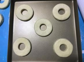 将已经成形的甜甜圈面片放入烤盘，盖保鲜膜放温暖湿润处进行第二次发酵。