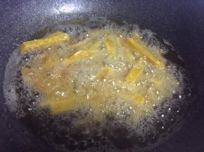 热锅倒油，油热倒入裹好淀粉的南瓜条炸制定型