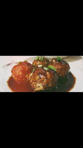 做好的酱汁淋在丸子表面，然后撒少许葱花装饰即可