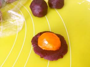 将紫薯馅跟奶黄馅分别分成10等份，将紫薯馅压扁，包裹上半颗蛋黄收好收口