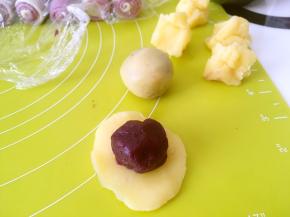 将奶黄馅压扁，包裹上紫薯蛋黄馅，收好收口