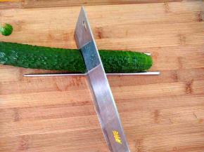 把黄瓜放入砧板上(一边垫上一根筷子，防止把黄瓜切断)，把刀成四十五度切片。