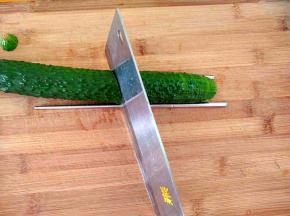 把黄瓜放入砧板上(一边垫上一根筷子，防止把黄瓜切断)，把刀成四十五度切片。