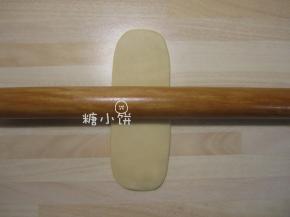 取一个擀卷过一次的面卷，收口朝下再次压扁擀开